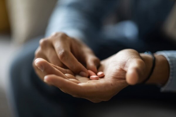 closeup shot of black man holding few pills in hand at home