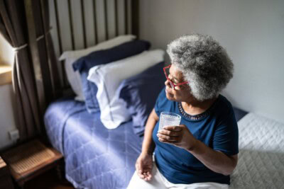 contemplative senior woman taking medicines at home