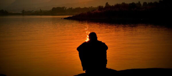 man sitting looking at the sunset