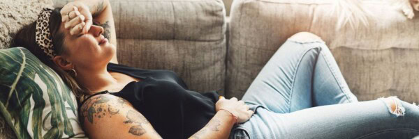 shot of a young woman experiencing stomach pain while lying on the sofa at home