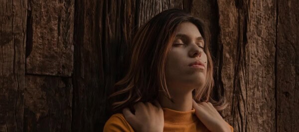 woman her eyes closed and massaging her shoulders