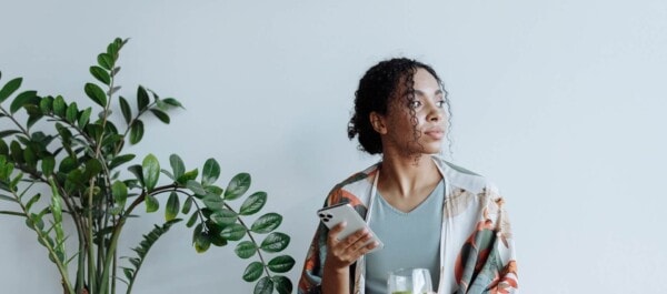 woman holding her phone while looking outside