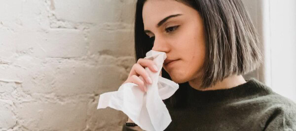 woman holding tissue to her nose
