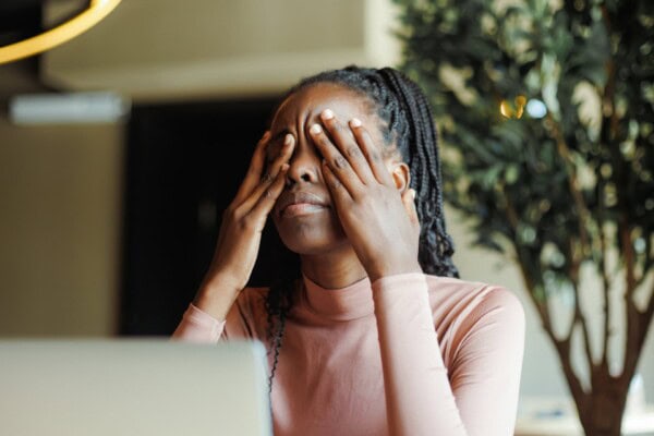 young unhappy african woman with dreadlocks crying covering eyes with hands in coffee house closeup. depressed black girl suffering, despaired, upset. tiredness, unfair, troubles